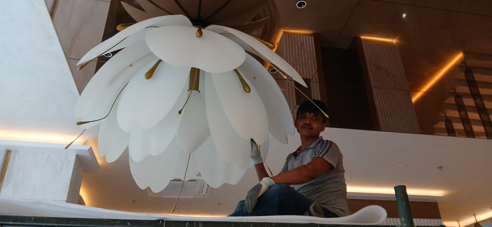Professional installation of a large white floral designer chandelier in a luxury residence by expert chandelier installers in India.